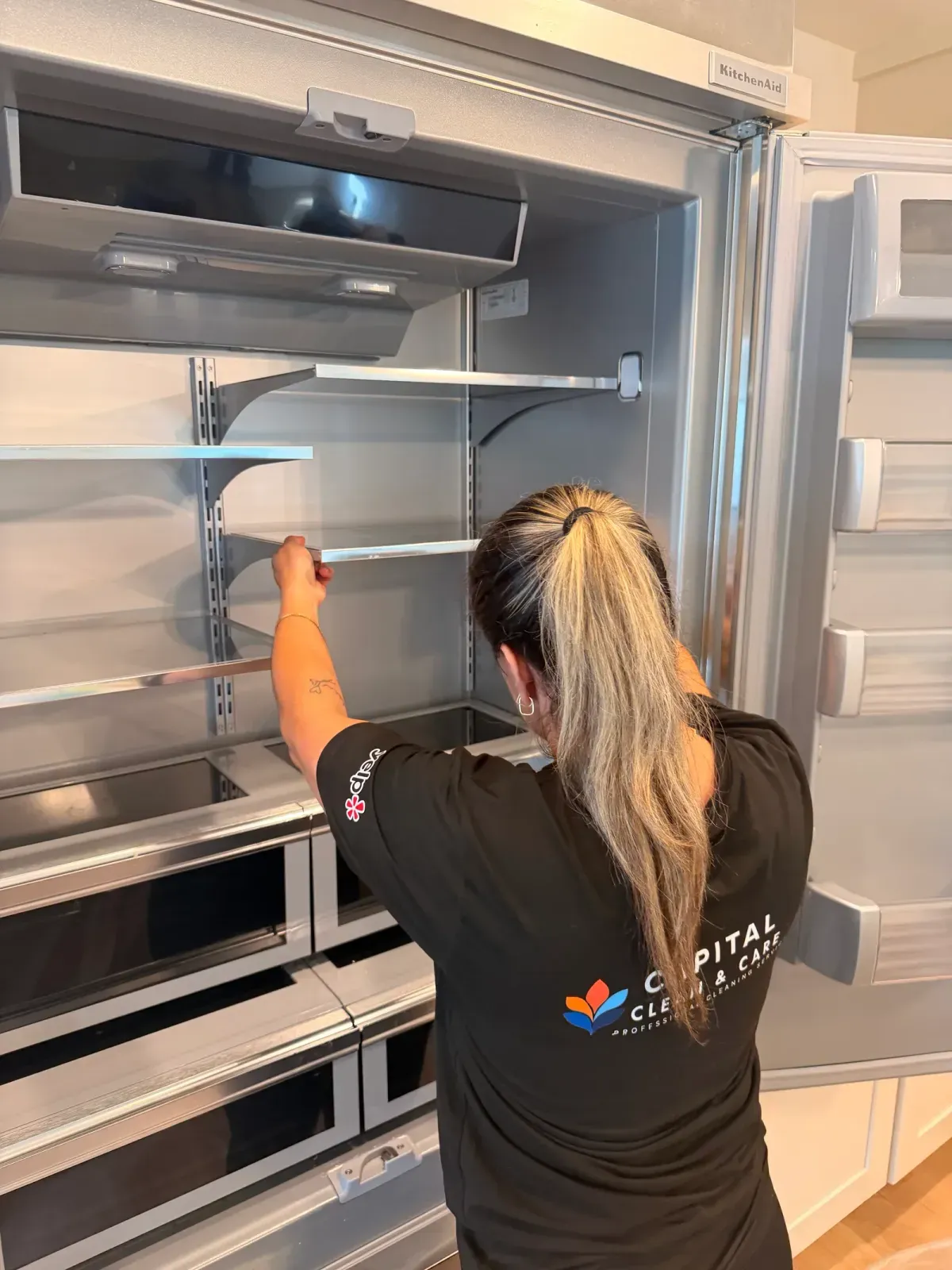 Team member cleaning the empty shelves inside the new refrigerator