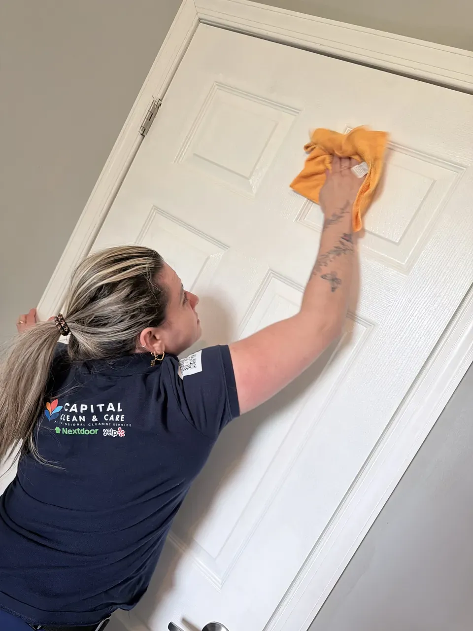 Capital Clean Care team member wiping the upper panel of an interior door