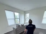Capital Clean Care employee mopping a hardwood floor in a bright bedroom