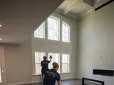 Capital Clean Care employee mopping the floor of an empty living room with tall windows