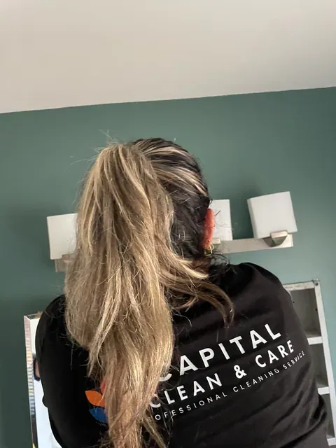 Capital Clean Care professional in uniform detailing the bathroom mirror and lighting area in a Rockville home
