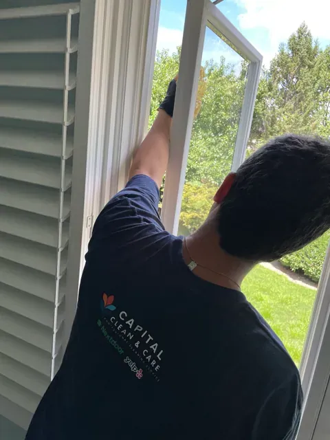 Capital Clean Care employee detailing the upper frame of an open window during a residential cleaning in Rockville, Maryland