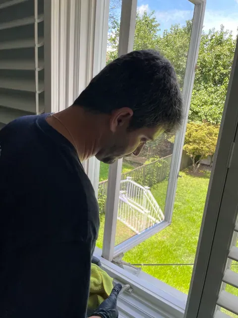 Capital Clean Care employee cleaning a window track and latch in a Rockville, Maryland home