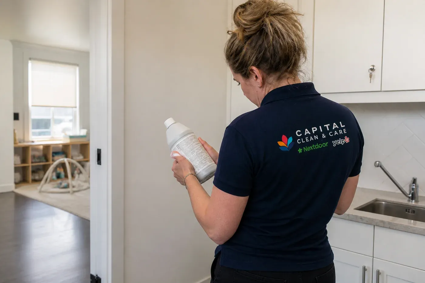 A Capital Clean Care team member in the navy company uniform reading the directions on a cleaning-product label before using it