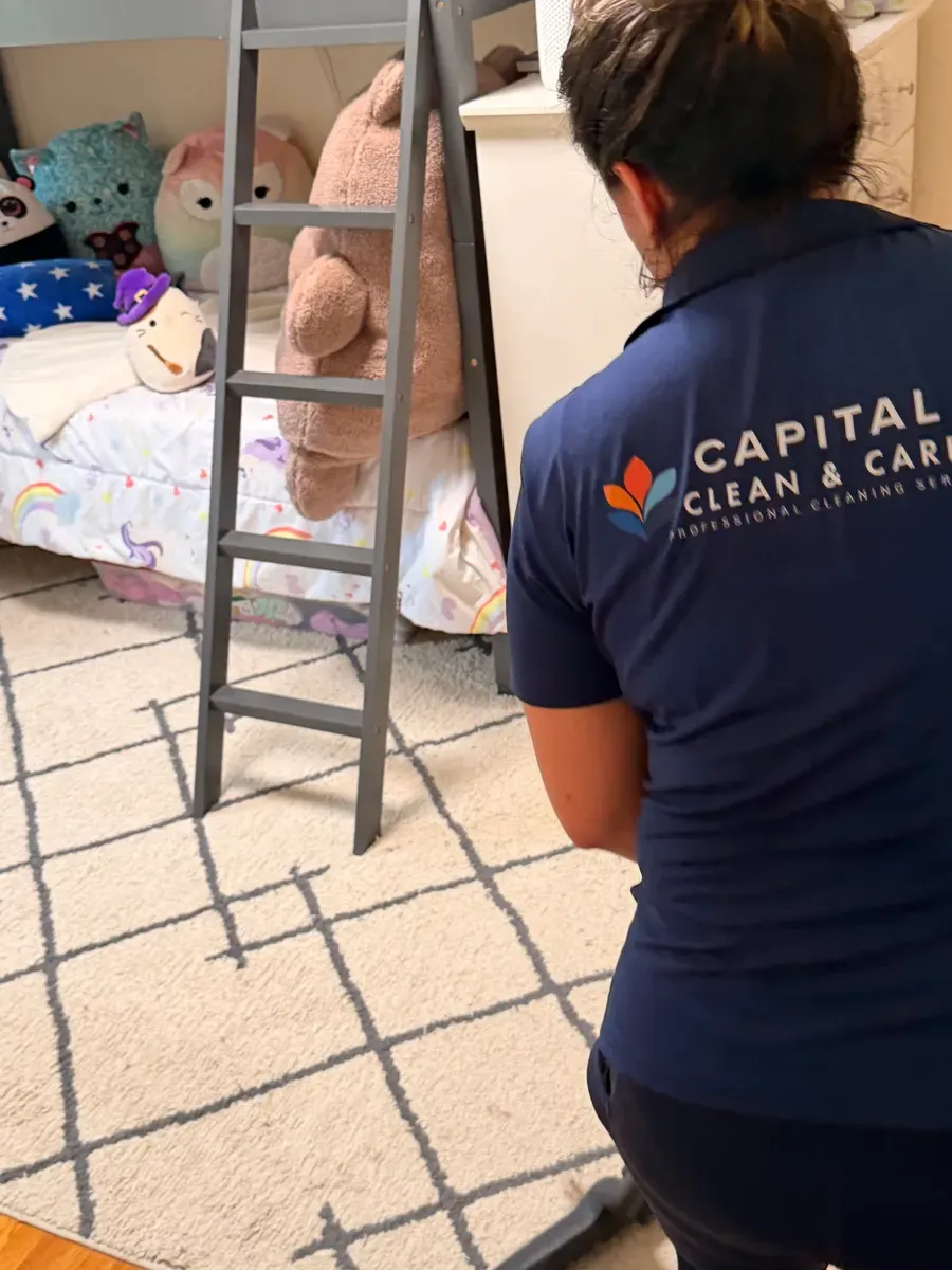 A Capital Clean Care team member in uniform cleaning a child's bedroom