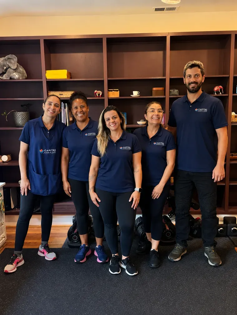 Five members of the Capital Clean Care team in navy uniforms, standing in a client's home.