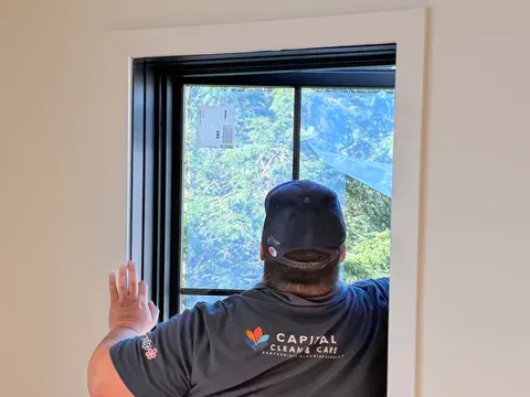 Capital Clean Care employee cleaning a window in a newly built room