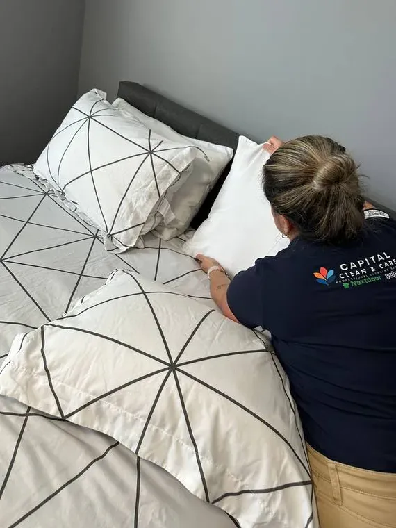 Capital Clean Care team member making a bed during a professional house cleaning visit